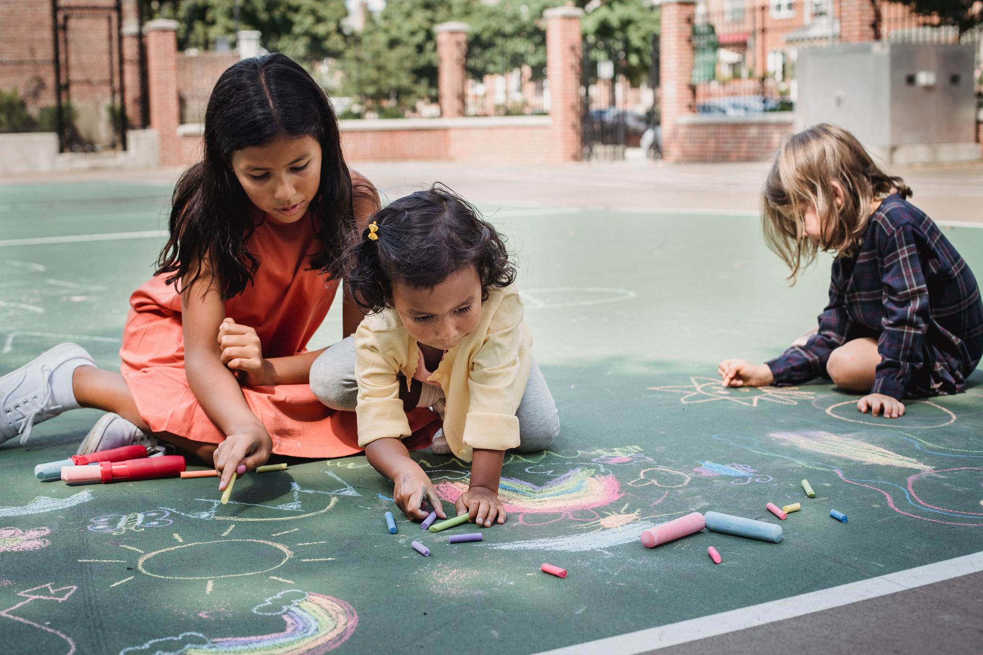 Children creating colorful chalk artwork outdoors